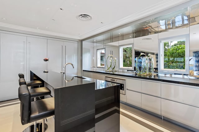 kitchen with a breakfast bar, white cabinetry, crown molding, and sink