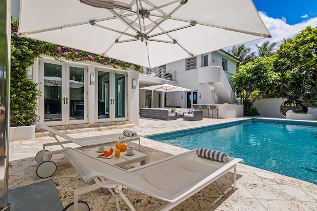 view of pool with an outdoor living space, a patio area, and french doors