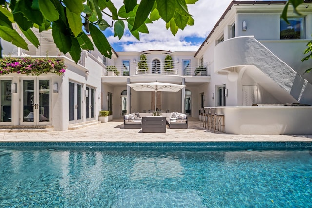 rear view of property featuring french doors, a balcony, exterior bar, outdoor lounge area, and a patio area