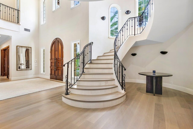 foyer with a towering ceiling and light wood-type flooring