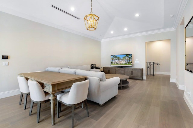 dining area with ornamental molding, lofted ceiling, an inviting chandelier, and light hardwood / wood-style flooring