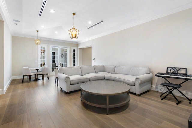 living room with hardwood / wood-style flooring, ornamental molding, a notable chandelier, and french doors