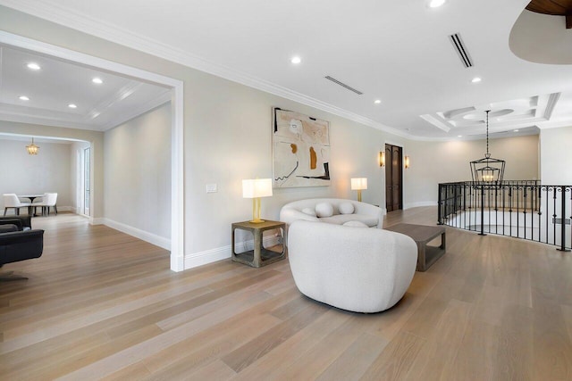 living room with light hardwood / wood-style flooring, ornamental molding, a raised ceiling, and a chandelier