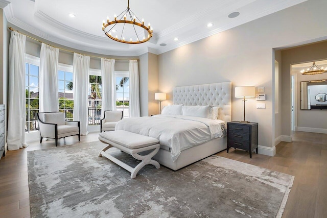 bedroom featuring a raised ceiling, crown molding, hardwood / wood-style flooring, and a notable chandelier