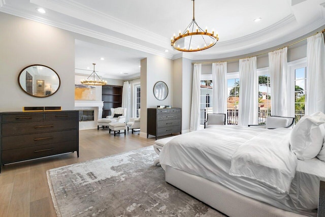 bedroom with crown molding, a notable chandelier, light wood-type flooring, and a tray ceiling