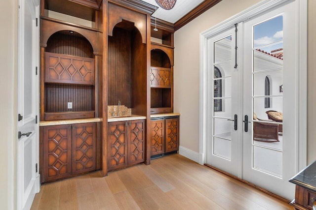 interior space with ornamental molding, sink, light wood-type flooring, and french doors