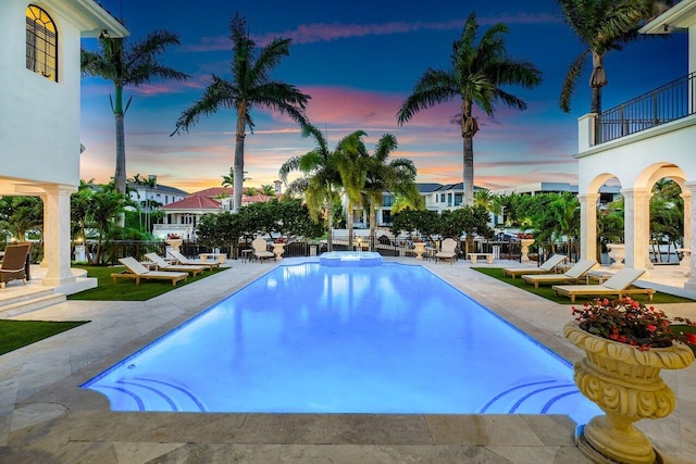 pool at dusk with a patio area