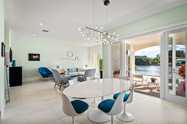 dining room featuring light tile patterned floors, a chandelier, a water view, and a healthy amount of sunlight