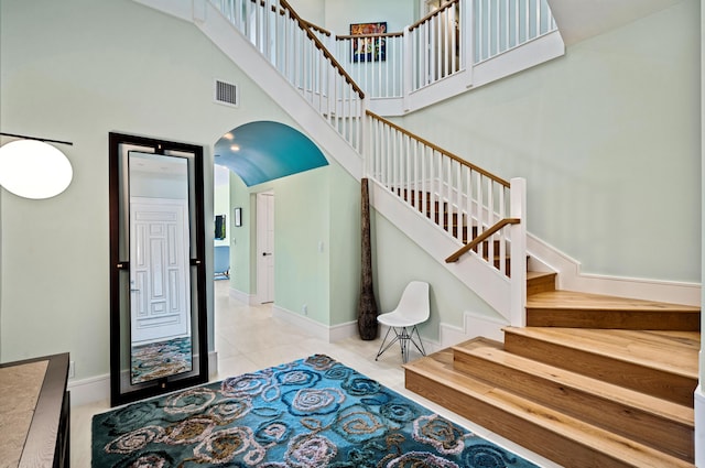 1583 Estuary Trl, Delray Beach, FL 33483 - stairs with tile patterned floors, arched walkways, baseboards, visible vents, and a high ceiling