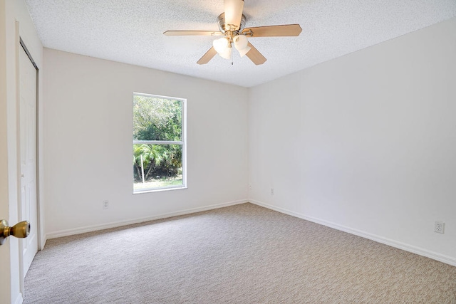 carpeted empty room with ceiling fan and a textured ceiling