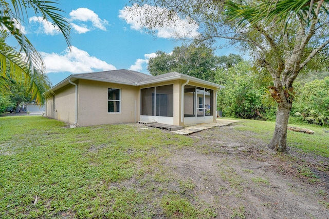 rear view of property featuring a lawn and a sunroom