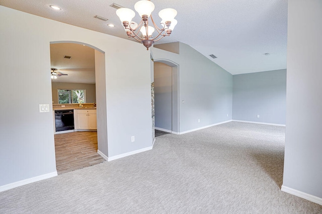 spare room with sink, ceiling fan with notable chandelier, a textured ceiling, light carpet, and lofted ceiling