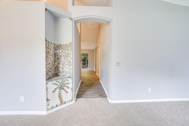 hallway with vaulted ceiling and carpet floors