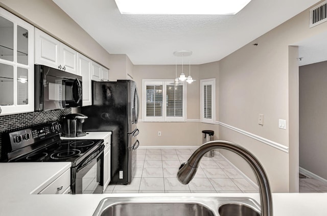 kitchen featuring sink, decorative light fixtures, white cabinetry, black appliances, and a notable chandelier