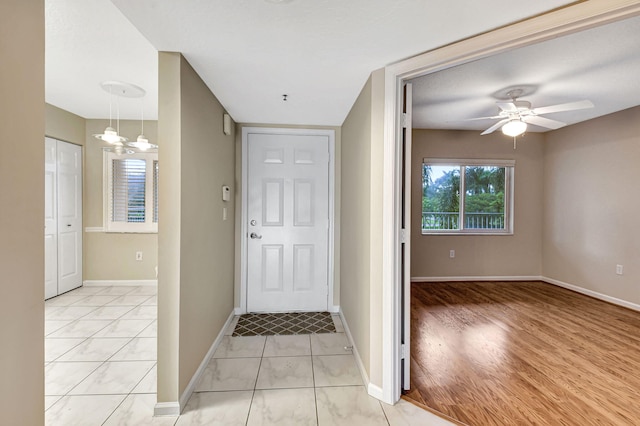 foyer entrance featuring ceiling fan with notable chandelier and light wood-type flooring