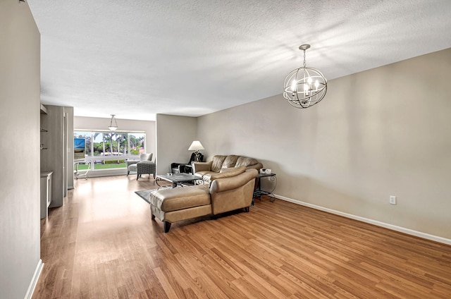 living room with an inviting chandelier, light hardwood / wood-style flooring, and a textured ceiling