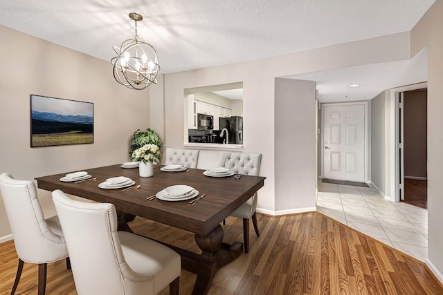 dining area featuring an inviting chandelier, a textured ceiling, and light wood-type flooring