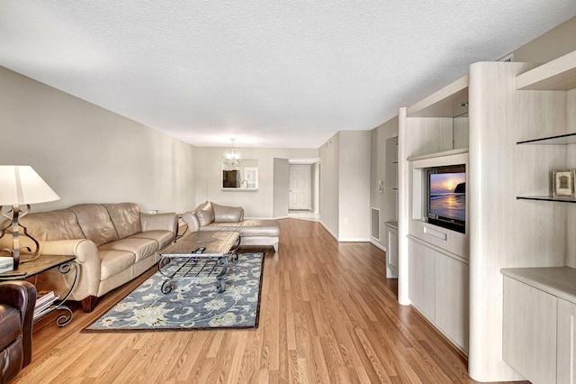 living room with a notable chandelier, light hardwood / wood-style floors, and a textured ceiling