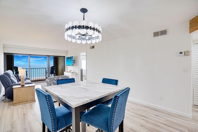 dining area with an inviting chandelier and light hardwood / wood-style flooring