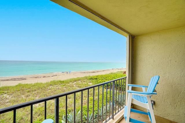 balcony featuring a view of the beach and a water view