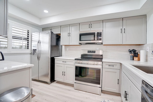 kitchen with light hardwood / wood-style flooring, decorative backsplash, and appliances with stainless steel finishes