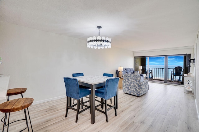 dining room with light hardwood / wood-style flooring, a textured ceiling, and an inviting chandelier