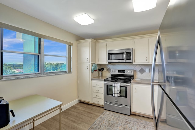 kitchen with stainless steel appliances, backsplash, white cabinetry, and light wood-type flooring