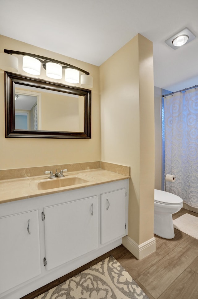 bathroom with walk in shower, hardwood / wood-style floors, vanity, and toilet