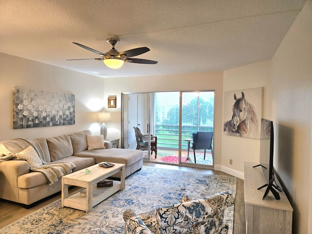 living room with ceiling fan, hardwood / wood-style flooring, and a textured ceiling