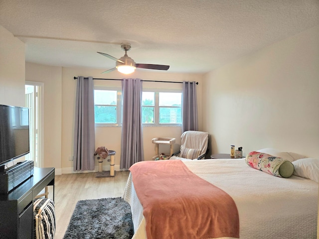 bedroom with a textured ceiling, ceiling fan, and light hardwood / wood-style flooring