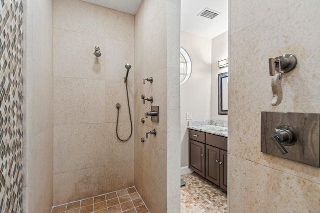 bathroom with a tile shower and vanity