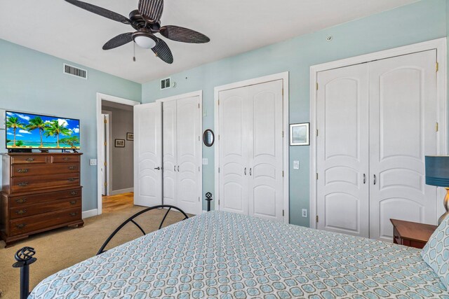 carpeted bedroom with ceiling fan and multiple closets