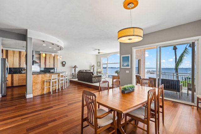 dining room featuring a water view, hardwood / wood-style flooring, and ceiling fan