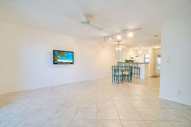 empty room featuring a textured ceiling, light tile patterned flooring, and ceiling fan