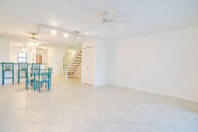 spare room featuring ceiling fan, a textured ceiling, track lighting, and light tile patterned flooring