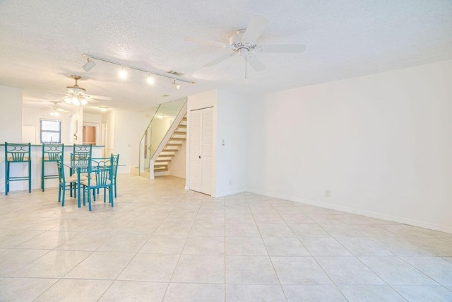 9427 S Ocean Dr Unit 60, Jensen Beach, FL 34957 - unfurnished room featuring a textured ceiling, stairway, ceiling fan, rail lighting, and light tile patterned floors