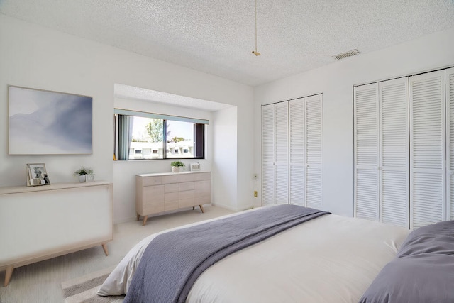 carpeted bedroom featuring two closets and a textured ceiling