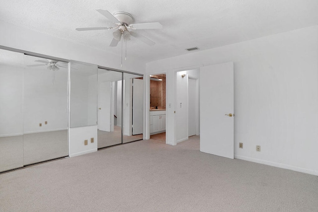 unfurnished bedroom with ensuite bath, ceiling fan, and light colored carpet