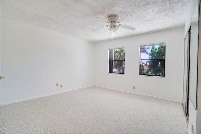 empty room featuring a textured ceiling, light colored carpet, and ceiling fan