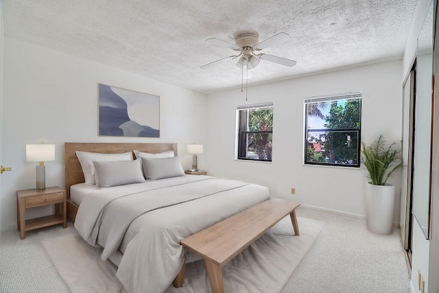 bedroom with a textured ceiling, ceiling fan, light colored carpet, and a closet