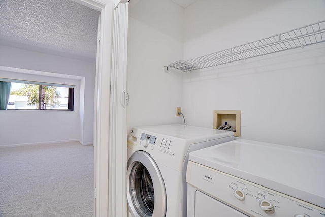 laundry area with a textured ceiling, carpet, and washing machine and clothes dryer