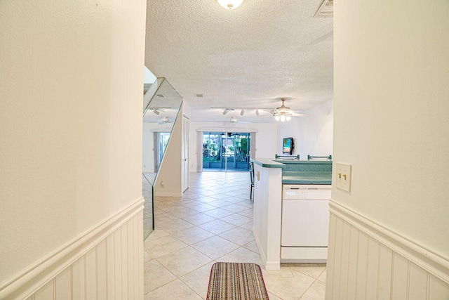 corridor featuring a textured ceiling, rail lighting, and light tile patterned floors