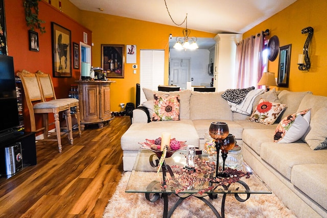 living room with a notable chandelier, vaulted ceiling, and dark hardwood / wood-style floors