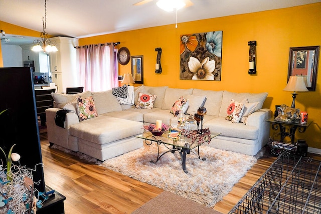 living room with ceiling fan with notable chandelier and hardwood / wood-style floors