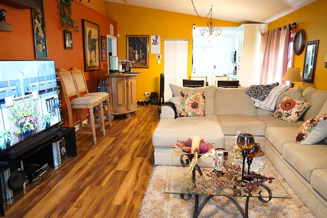 living room with a notable chandelier, lofted ceiling, and hardwood / wood-style floors