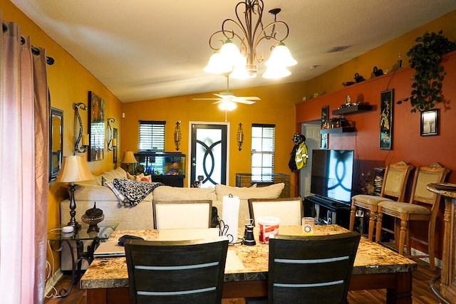 dining area featuring ceiling fan with notable chandelier, vaulted ceiling, and dark wood-type flooring