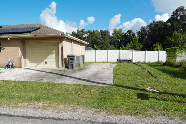 view of side of home with central AC, a yard, solar panels, and a garage