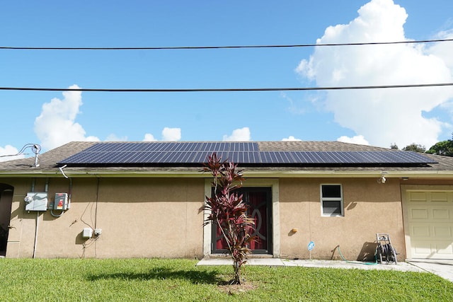 view of front facade featuring a front yard, a garage, and solar panels