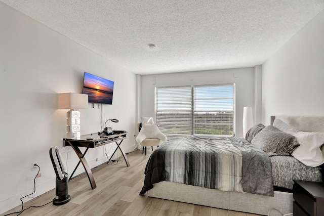 bedroom with a textured ceiling and light hardwood / wood-style flooring