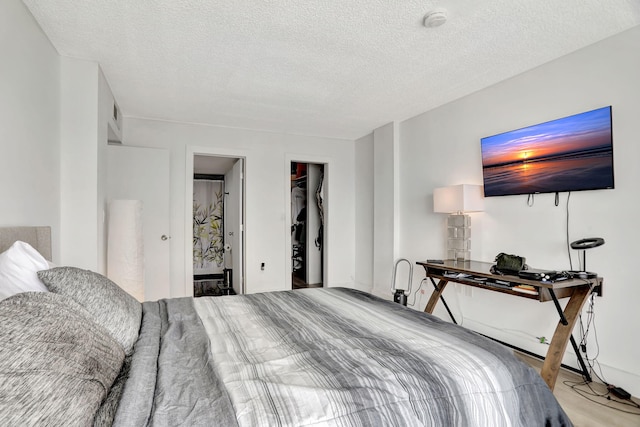 bedroom with ensuite bathroom, a spacious closet, and a textured ceiling